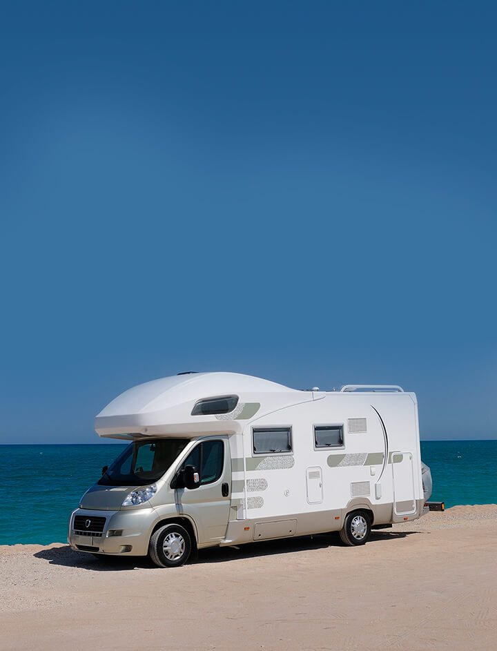 Witte camper op een strand aan zee