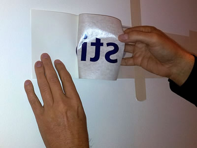 Een hand trekt de applicatietape met letters van het rugpapier